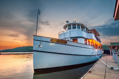 A large boat named "Liberty" docked at sunset, reflecting warm colors on the water.