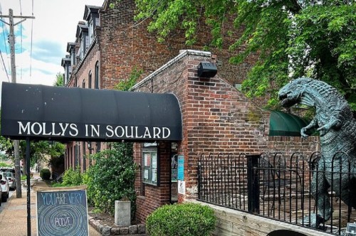 Entrance to Molly's in Soulard, featuring a brick facade and a Godzilla statue beside the entrance.