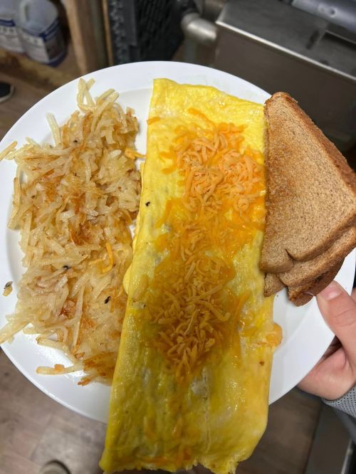 A plate with a cheese omelet, crispy hash browns, and a slice of toasted bread.