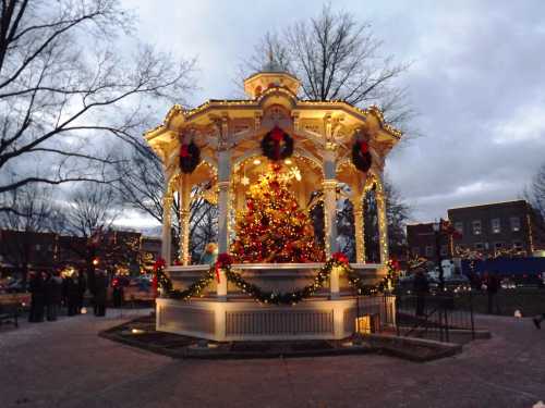 A beautifully decorated gazebo with a Christmas tree, surrounded by festive lights and winter scenery.