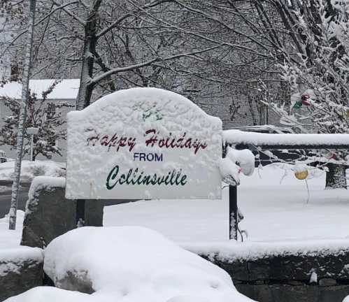 A snowy sign reads "Happy Holidays from Collinsville," surrounded by winter scenery and trees.