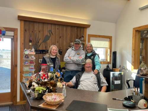 Four people pose together in a cozy reception area, surrounded by decorations and a welcoming atmosphere.