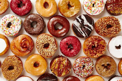 A colorful assortment of various donuts, including glazed, chocolate, and sprinkled varieties, arranged neatly.