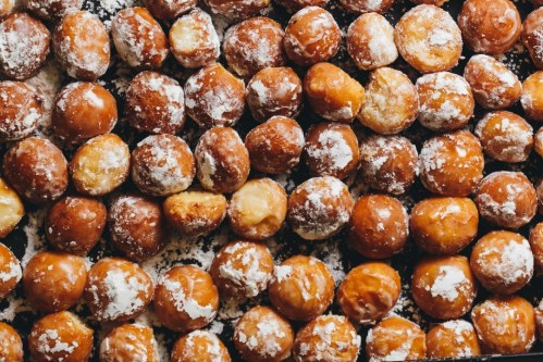 A close-up view of a tray filled with powdered sugar-covered doughnuts.