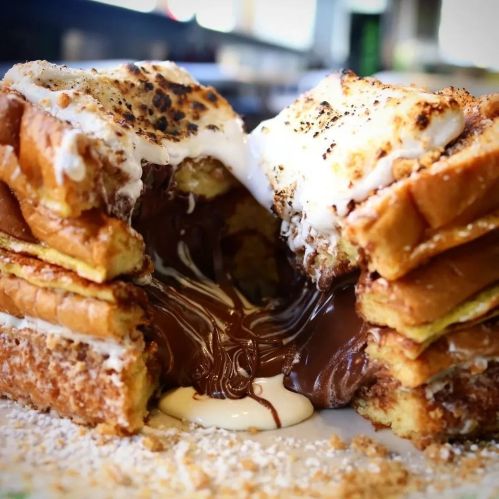 A decadent dessert featuring toasted bread filled with melted chocolate and marshmallow, topped with graham cracker crumbs.