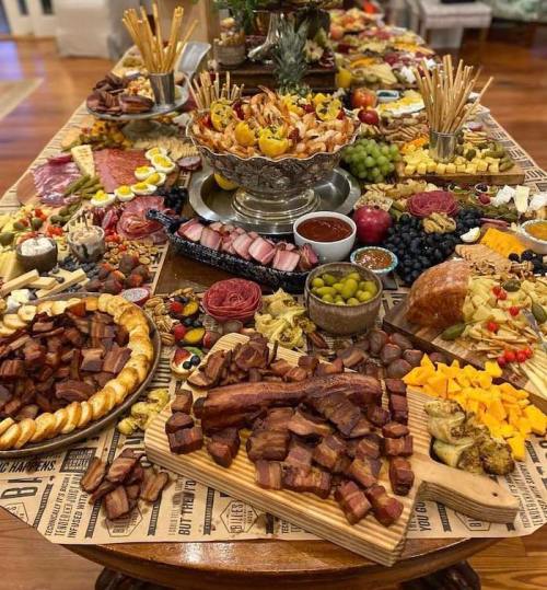 A lavish spread of assorted meats, cheeses, fruits, and snacks arranged on a large table for a festive gathering.