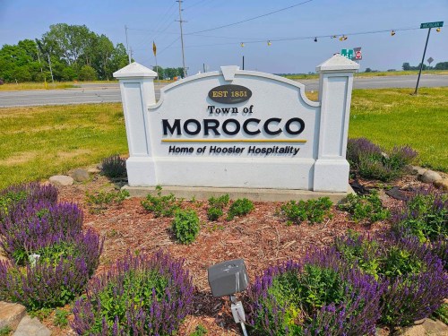 Sign for the Town of Morocco, established in 1851, featuring the phrase "Home of Hoosier Hospitality" surrounded by greenery.