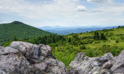 A scenic view of rolling green hills and distant mountains under a partly cloudy sky.