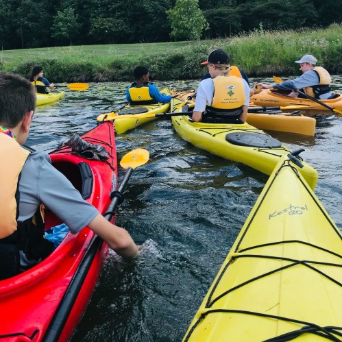 A group of people kayaking in colorful kayaks on a calm waterway surrounded by greenery.