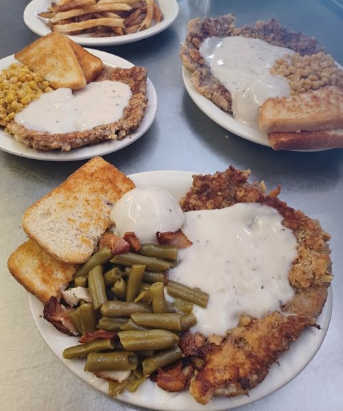 Three plates of comfort food featuring fried chicken, gravy, green beans, corn, toast, and fries.