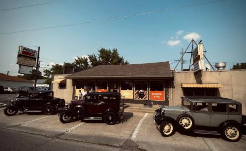 A vintage diner with classic cars parked outside under a clear blue sky.