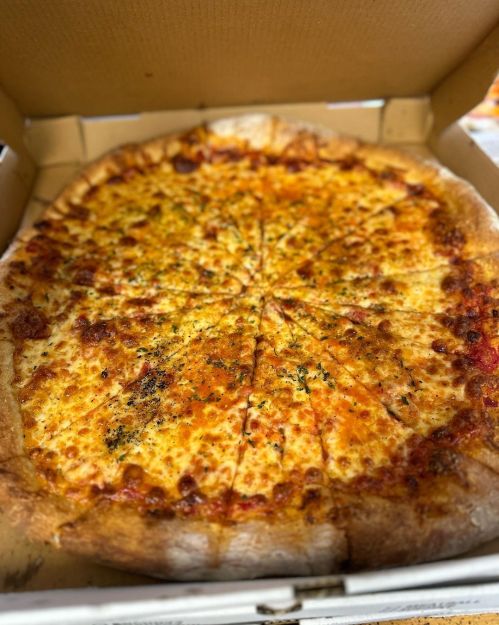 A freshly baked cheese pizza in a cardboard box, sliced into equal pieces with a golden crust.