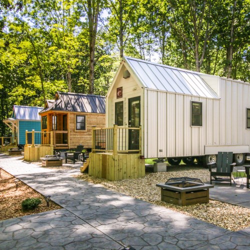 A row of tiny houses with a pathway, surrounded by greenery and outdoor seating areas.