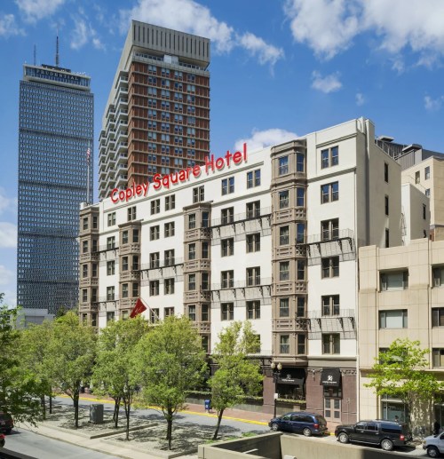 Copley Square Hotel building with modern skyscrapers in the background and clear blue sky.