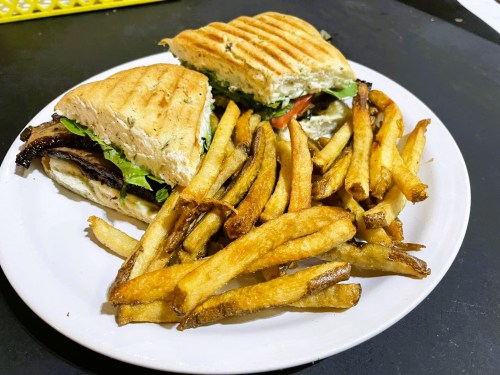 A plate with a toasted sandwich filled with lettuce and tomato, accompanied by a side of golden French fries.