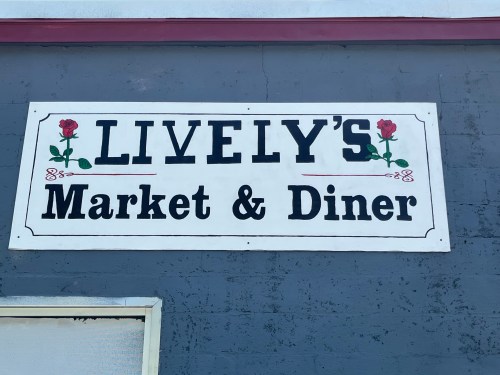 Sign for "Lively's Market & Diner" featuring roses, displayed on a gray wall.