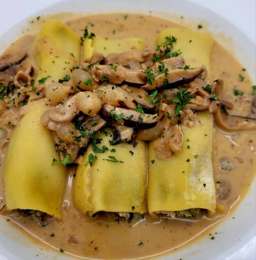 Plate of stuffed pasta with creamy sauce, mushrooms, and herbs, garnished with parsley.