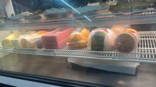 Various types of packaged cheese and deli meats displayed in a refrigerated case.