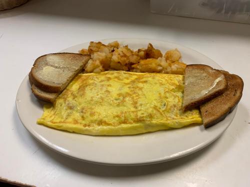 A plate with a fluffy omelet, golden hash browns, and two slices of toasted bread.