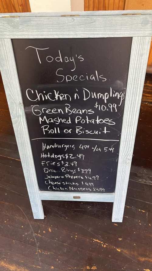 A chalkboard menu listing today's specials: Chicken & Dumplings, Green Beans, Mashed Potatoes, and more with prices.