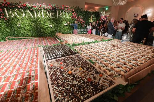 A large display of colorful desserts arranged in a decorative setting, with guests admiring the spread.
