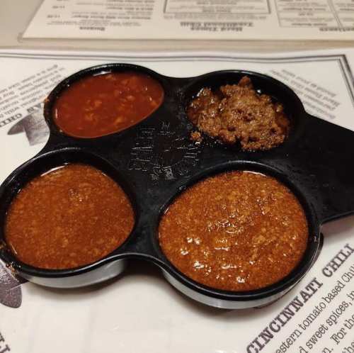 Three small containers of different chili sauces on a menu background.