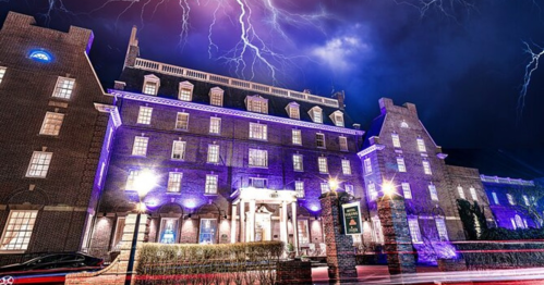 A historic building illuminated in purple under a stormy sky with lightning, creating a dramatic nighttime scene.