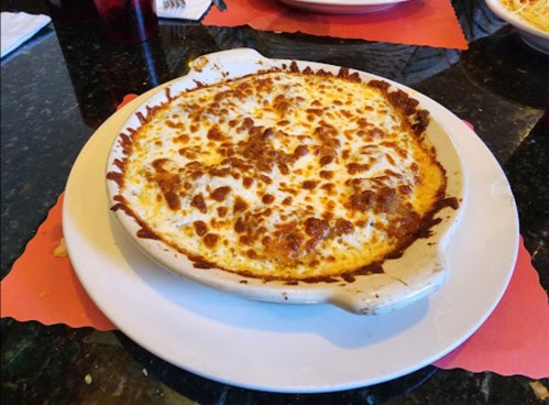 A baked dish with a golden, cheesy topping and a rich, meaty filling, served in a white ceramic dish.