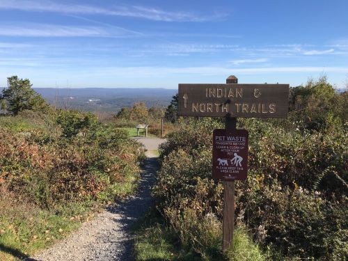 Signpost indicating Indian and North Trails, with a scenic view of hills in the background and a path leading forward.