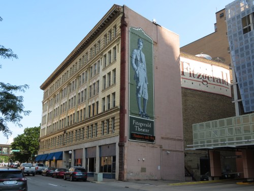 Historic Fitzgerald Theater building with a large mural and adjacent modern structure in a city setting.