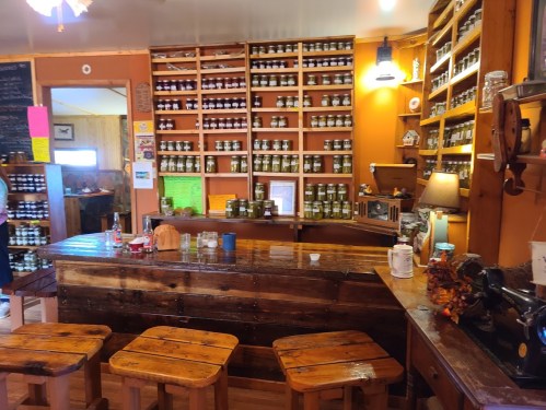 Cozy shop interior with wooden shelves filled with jars, a rustic counter, and warm lighting.