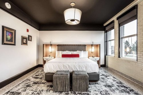 Modern bedroom featuring a large bed, stylish decor, and large windows with natural light.