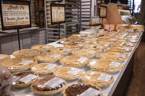 A display of various Shoofy Pies in clear packaging on a table, with signs indicating flavors.