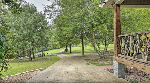 A winding path leads through a green landscape with trees, viewed from a porch with wooden railings.