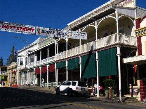Historic buildings with green awnings and a festival banner, set against a clear blue sky.