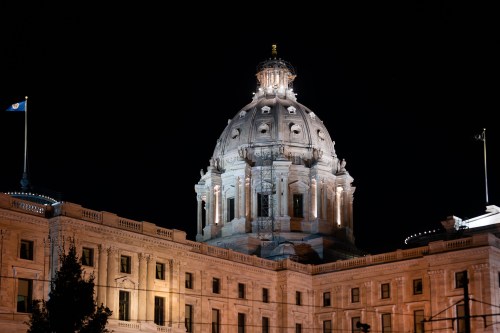 The illuminated dome of a historic building at night, showcasing architectural details against a dark sky.
