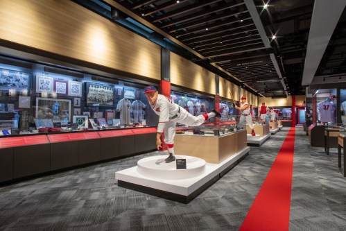 A sports museum exhibit featuring displays of memorabilia, uniforms, and a life-sized statue of a baseball player.