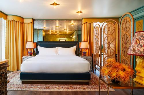 A stylish bedroom featuring a large bed, colorful curtains, decorative lamps, and a vibrant rug.