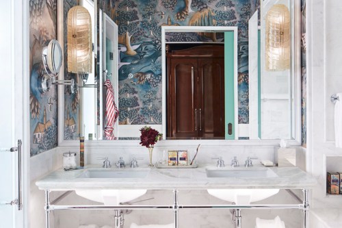 A stylish bathroom featuring dual sinks, elegant lighting, and a vibrant mural on the walls.