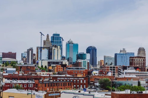 A city skyline featuring a mix of modern skyscrapers and historic buildings under a cloudy sky.