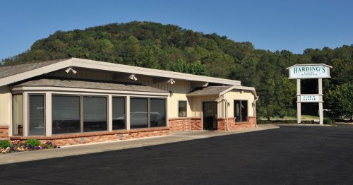 A single-story building with large windows, surrounded by greenery, featuring a sign that reads "Harding's."