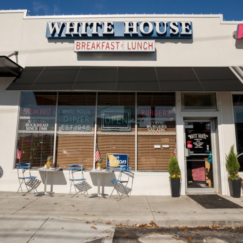 Exterior of the White House Diner, featuring a sign for breakfast and lunch, with outdoor seating and an open sign.