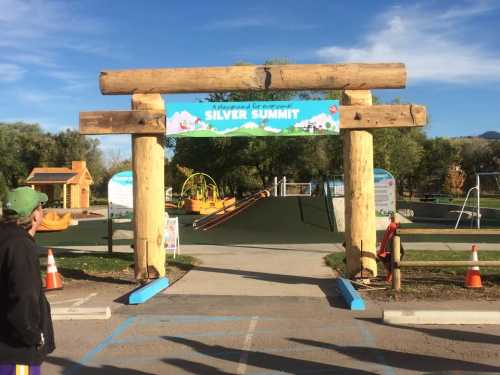 Entrance to Silver Summit playground, featuring wooden archway and play equipment in a sunny outdoor setting.