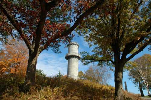 A tall stone tower surrounded by colorful autumn trees against a blue sky.