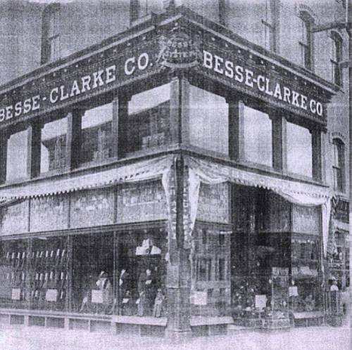 Historic storefront of Besse-Clarke Co., featuring large windows and signage, in a vintage black-and-white photo.