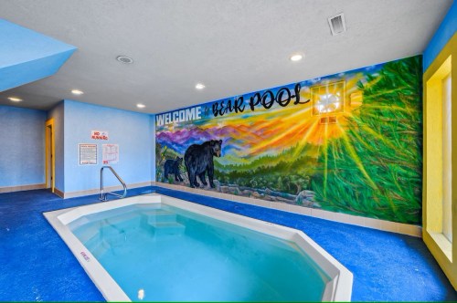 Indoor pool area with a mural of bears and a sunset, featuring bright blue walls and a welcoming atmosphere.