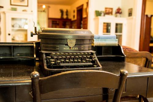 A vintage typewriter on a wooden desk, with a cozy room in the background.