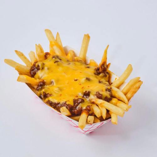 A serving of loaded fries topped with melted cheese and chili in a red and white paper tray.