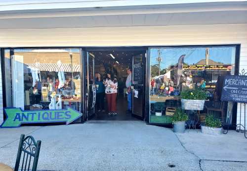 A storefront with an "Antiques" sign, showcasing a variety of items and people inside browsing.