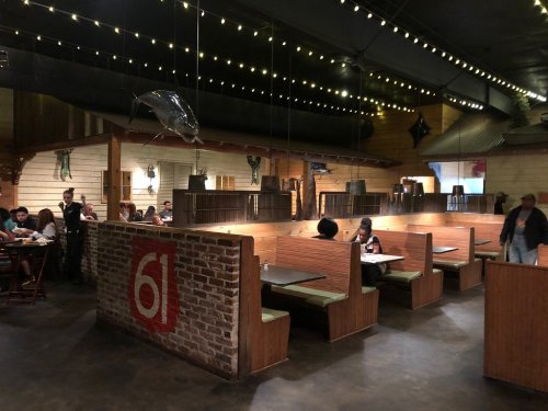 Interior of a restaurant featuring wooden booths, dim lighting, and decorative elements like fish and string lights.